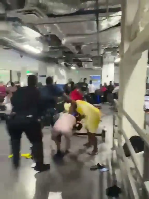 Segundo fotograma del vídeo de Breaking911: agentes y pasajeros en el forcejeo dentro del terminal de aduana de PortMiami