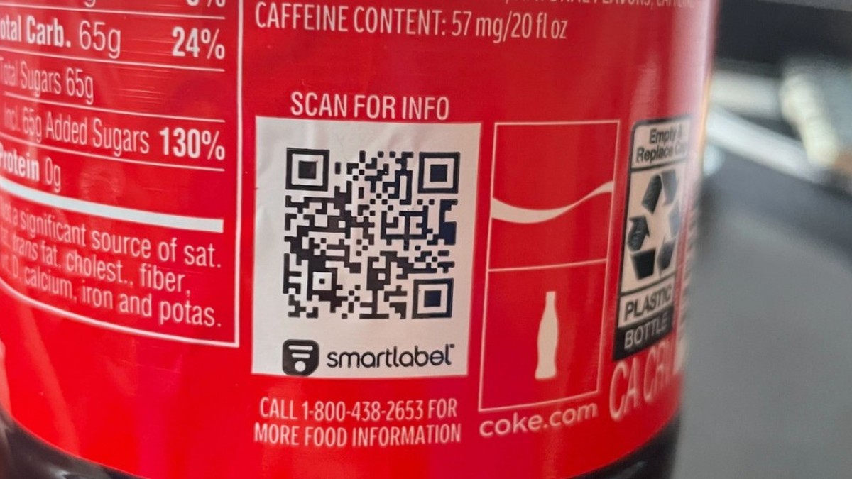 Etiqueta de una botella de Coca-Cola con código QR SmartLabel y el texto «SCAN FOR INFO» junto a datos nutricionales; las grandes marcas de refrescos ampliarán el enlace a ingredientes