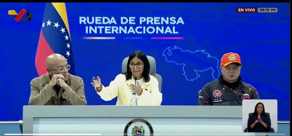 Delcy Rodríguez, al centro, durante la rueda de prensa internacional del 2 de julio de 2026, flanqueada por Jorge Rodríguez y Diosdado Cabello, con la bandera y el mapa de Venezuela al fondo
