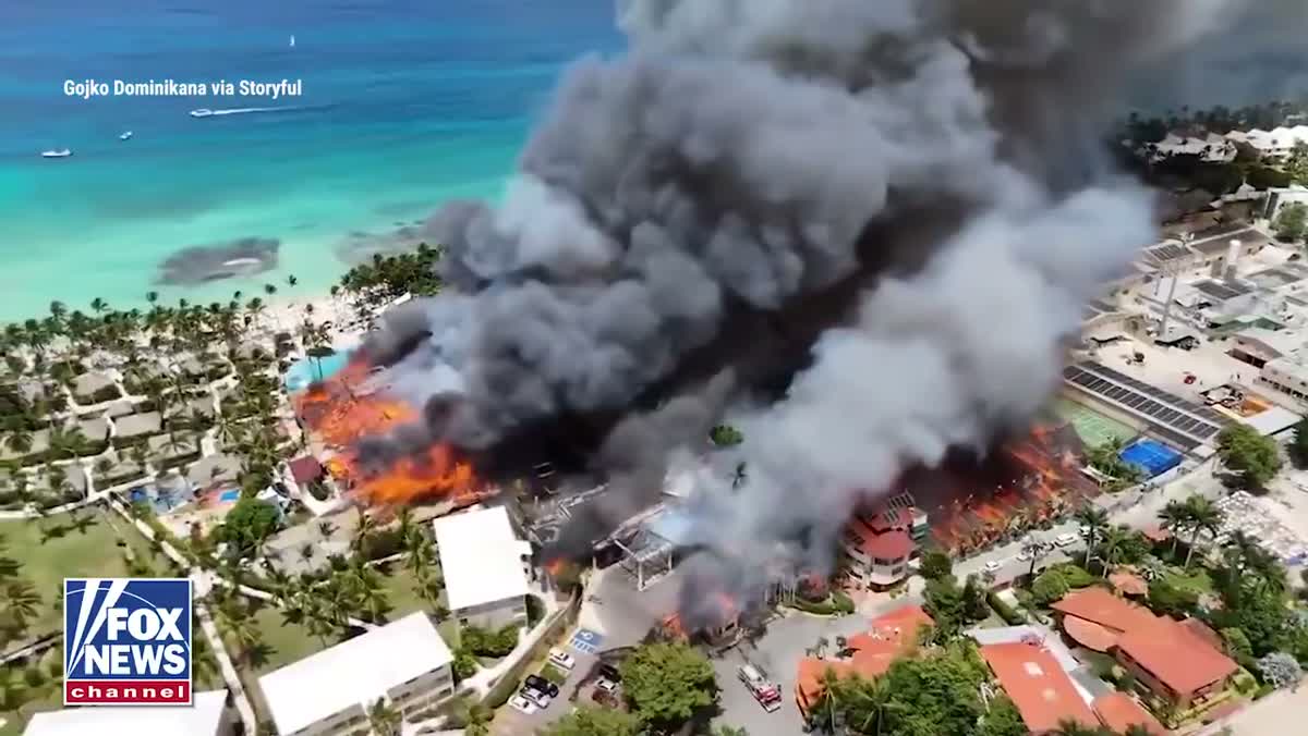 Llamas altas consumiendo el techo de palma del Viva Wyndham Dominicus Beach mientras equipos de emergencia intervienen