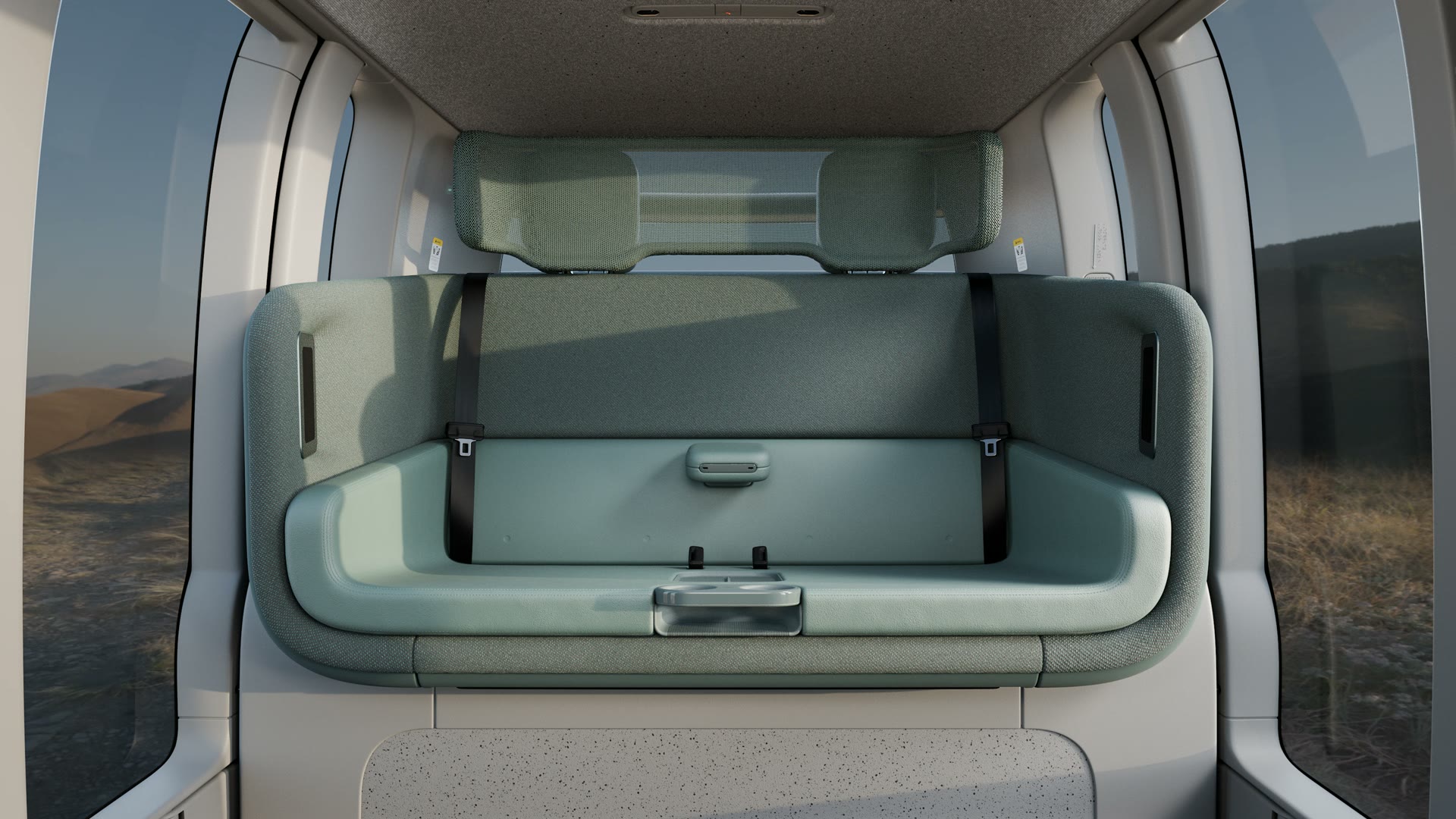 Interior del robotaxi Zoox renovado: asientos verde aloe en disposición carruaje y acabados en gris piedra